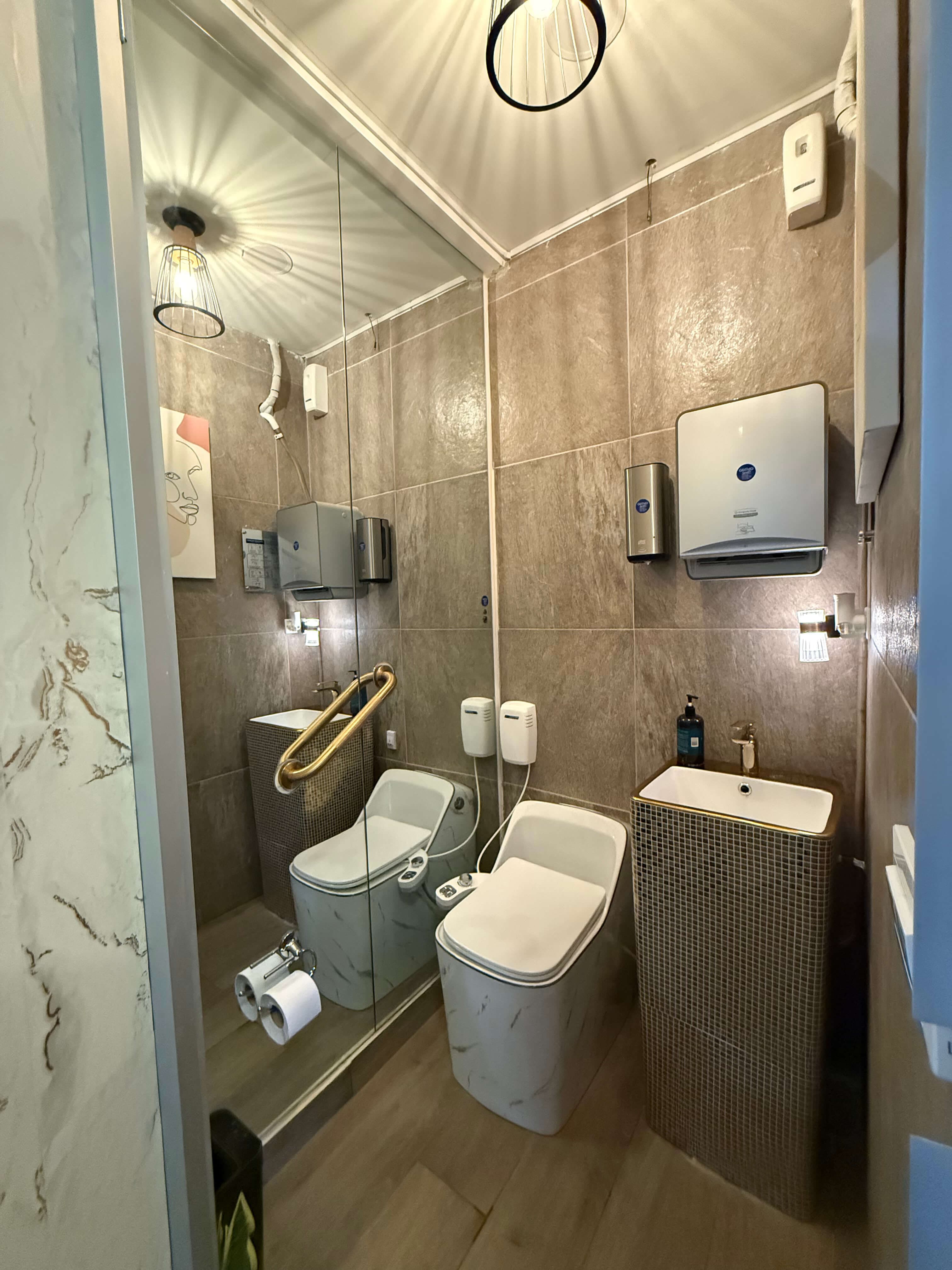Baño para pacientes de OrthoSmile con acabados en piedra y lavamanos en mosaico